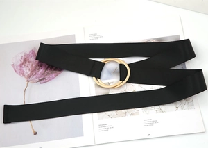 Detail of minimalist black fabric belt with golden double ring buckle on a fashion magazine