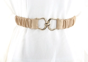 Dettaglio di cintura elastica beige con fibbia in metallo dorato a forma di ferro di cavallo