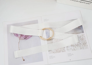 Detail of white woven canvas belt with gold double ring buckle on a magazine page