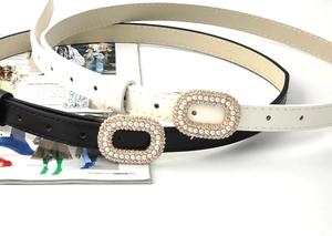 Détail des boucles élégantes avec perles et strass sur ceintures fines en cuir noir et blanc