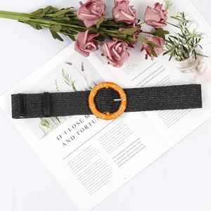Macro detail of black woven straw belt featuring a vintage round buckle on a magazine