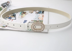 Détail d'une élégante ceinture fine blanche avec boucle ovale en perles et strass