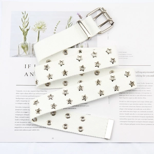 Detailed macro view of white canvas belt with star-shaped eyelets and double-prong buckle