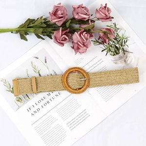 Detail of bohemian wide braided straw belt with large round buckle on aesthetic background
