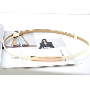 Fine ceinture beige minimaliste pour femme avec boucle dorée sur un magazine de mode