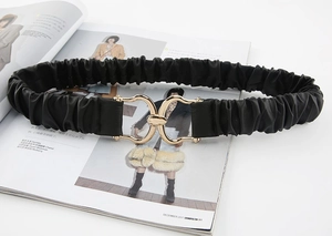 Dettaglio della cintura elastica nera con fibbia dorata e texture in pelle goffrata