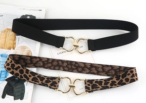 Flat lay of black and leopard print elastic belts with interlocking gold metal buckles