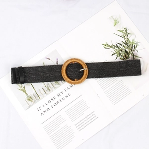 Detail of bohemian woven belt with round straw buckle and metal pin on a fashion magazine