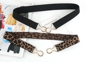 Detail of black and leopard print elastic waist belts with interlocking gold metal buckles