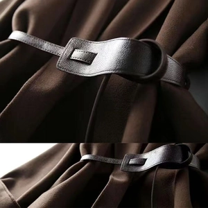 Detail of a deep brown coat waist featuring a litchi textured leather belt and wool fabric