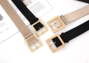 Detail view of velvet belts in black and beige with textured golden square buckles