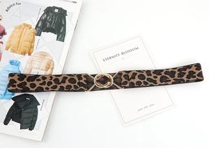 Detail of leopard print elastic belt with gold interlocking ring buckle on a white surface