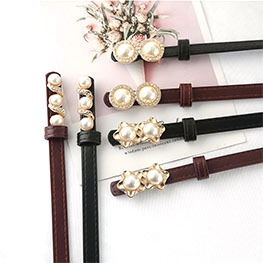 Detail of luxury thin waist belts featuring pearl buckles and rhinestone accents in black and burgundy