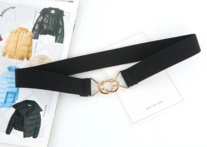 Detail of black elastic waist belt featuring a polished gold double ring metal buckle