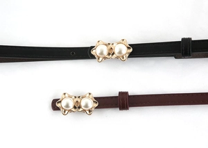 Detail of elegant waist belts in black and burgundy with pearl gold buckles