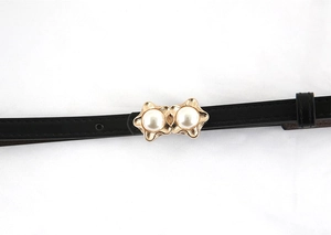 Close-up of black leather belt with golden petal buckle and dual white pearls detail