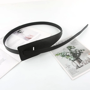 Close-up of a stylish black leather belt with lychee texture and rectangular gold buckle