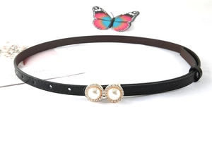 Detailed close-up of thin black waist belt featuring gold dual pearl and rhinestone buckle