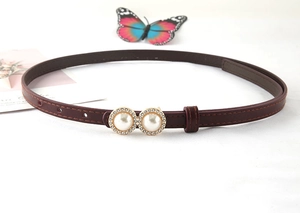 Macro detail of wine red skinny belt with elegant pearl and rhinestone double ring buckle