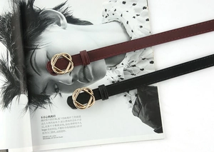 Close-up of elegant burgundy and black thin belts with gold interlocking buckles
