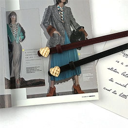 Detail showing red and black thin belts with golden heart buckles on a magazine