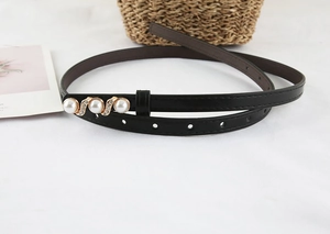 Macro detail of slim black waist belt with wave-set pearls and rhinestones on gold buckle