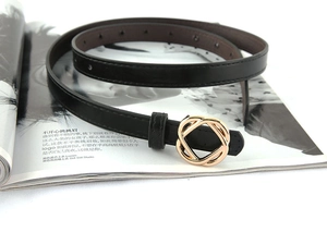 Detail of a thin black leather belt with intertwined gold geometric metal buckle