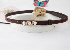 Close-up of a brown leather belt with gold buckle and elegant pearl embellishments