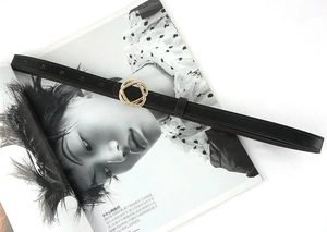 Detail of a thin black leather belt with a minimalist golden interlocking circle buckle