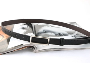Detail of slim black leather belt with silver rectangular buckle on a fashion magazine