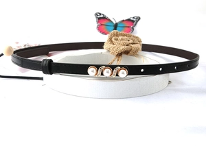 Close-up of slim black PU leather belt with elegant pearl and rhinestone buckle