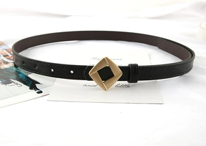 Detail of black leather waist belt showing the textured strap and gold geometric buckle