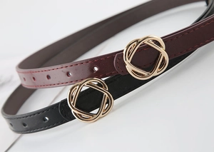 Detail of burgundy and black slim waist belts with interlaced golden metal buckles