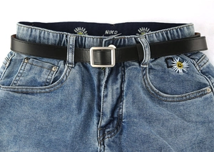 Detailweergave van de blauwe damesjeans met madeliefjesborduursel en zwarte riem met vierkante gesp