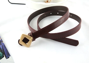 Detail view of the deep wine red belt with a golden square metal buckle and fine stitching