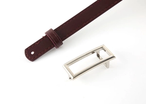 Macro detail of wine red leather belt with polished silver rectangular metal buckle