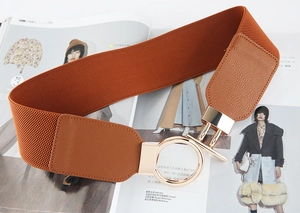 Detail of caramel brown elastic wide belt with round gold buckle and pebble leather