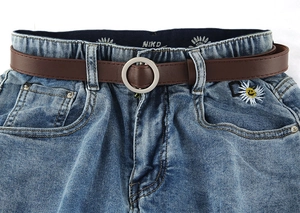 Detail van blauwe denim jeans met elastische taille, bruine riem en klein geborduurde madeliefje