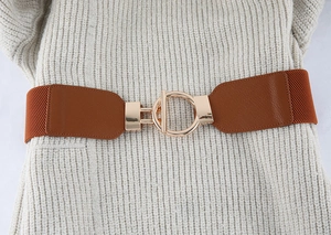 Detail view of a brown elastic waist belt with a golden circular metal buckle on white fabric