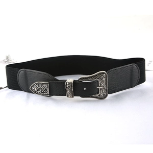 Dettaglio di fibbie vintage incise in argento e pelle su cintura elastica nera da donna