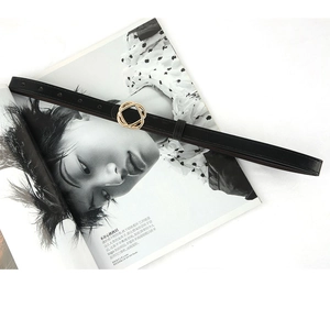 Minimalist black leather skinny belt for women with golden interlocking buckle on magazine