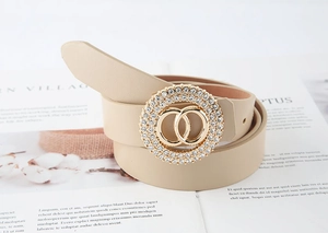 Dettaglio cintura beige da donna con fibbia a doppio anello dorato e strass scintillanti