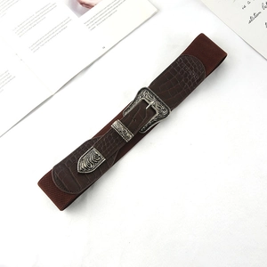 Dettaglio della fibbia incisa in argento vintage su cintura elastica marrone scuro