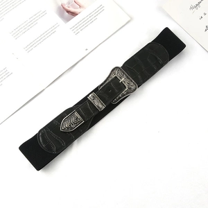 Dettaglio della fibbia vintage in argento con incisioni su cintura elastica nera