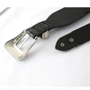 Dettaglio cintura elastica nera vintage con fibbia in metallo argento e viti decorative