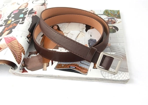 Detailopname van een donkerbruine leren riem met zilveren gesp op een modetijdschrift