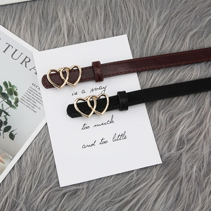 Close-up of golden double heart buckles on black and burgundy slim leather belts