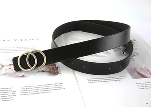 Détail de la ceinture en cuir noir avec boucle double anneau dorée mate et trous de réglage