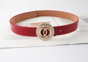 Dettaglio cintura in pelle rossa con doppi anelli dorati e fibbia con strass brillanti