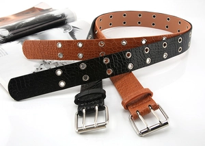 Close-up of punk style double grommet belt with crocodile embossed leather texture